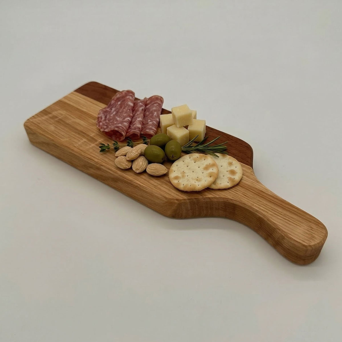 Wooden cutting board with assorted meats, cheeses, and crackers on a white background