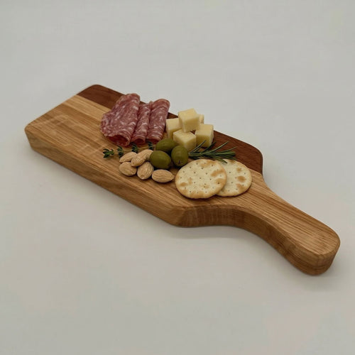 Wooden cutting board with assorted meats, cheeses, and crackers on a white background