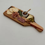 Wooden charcuterie board with cured meats, cheese, and olives on a light gray background