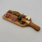 Wooden charcuterie board with cured meats, cheese, and fruits on a white background