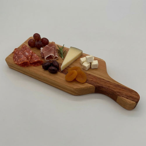 Wooden charcuterie board with cured meats, cheese, and dried fruits on a white background