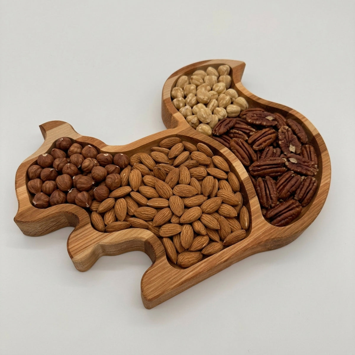 Wooden tray shaped like a squirrel filled with various nuts on a white background