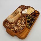 Wooden snack tray with crackers, nuts, olives, and cheese on a white background
